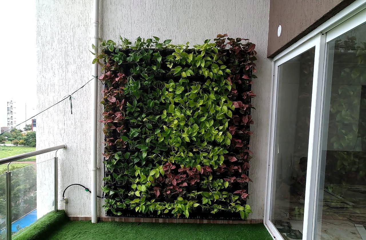 A planted green wall filling the end of an apartment balcony