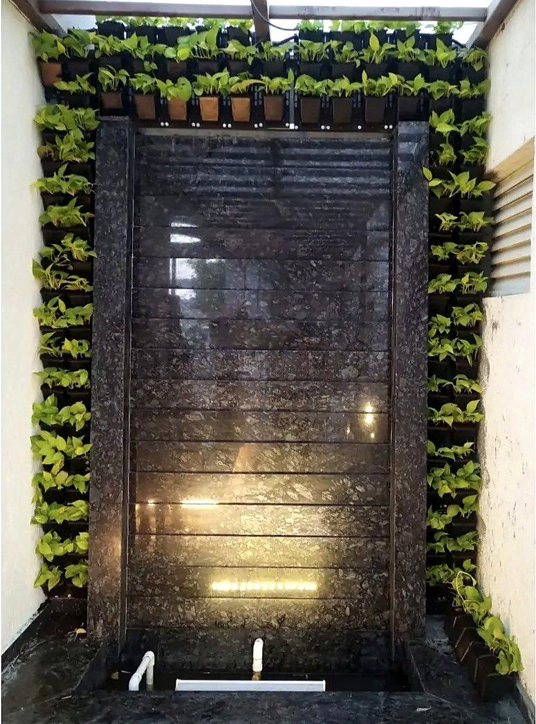 A polished granite water wall framed on three sides by planted pockets